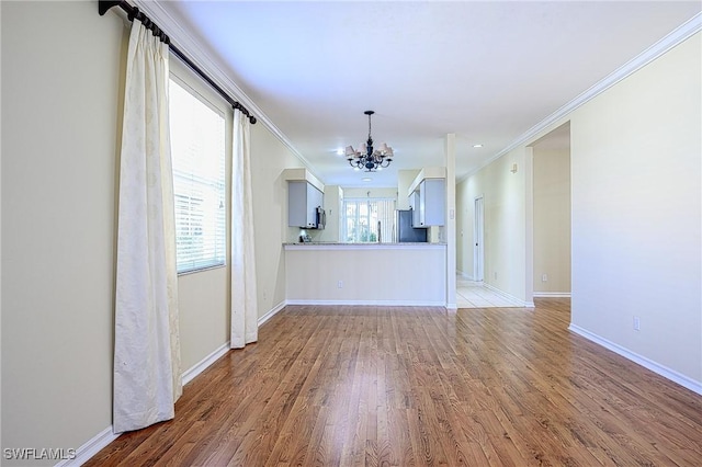 unfurnished living room featuring light hardwood / wood-style flooring, ornamental molding, and an inviting chandelier