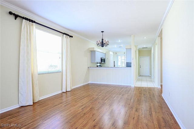 unfurnished living room featuring light hardwood / wood-style flooring, a notable chandelier, and ornamental molding