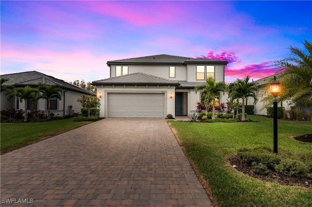 view of front facade featuring a garage, decorative driveway, and a lawn