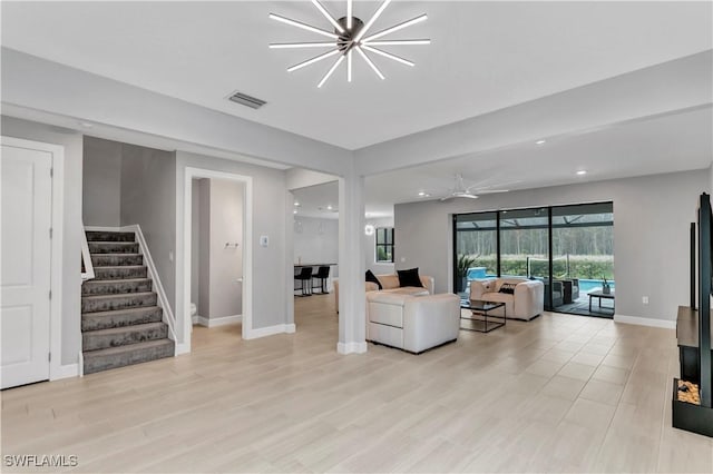 living room with light wood-type flooring and ceiling fan with notable chandelier