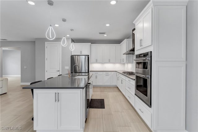 kitchen featuring decorative light fixtures, decorative backsplash, white cabinetry, a kitchen island with sink, and stainless steel appliances