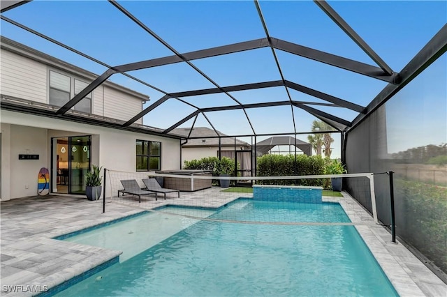 view of swimming pool featuring glass enclosure, a hot tub, and a patio