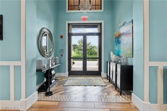 entryway with hardwood / wood-style flooring, a chandelier, and french doors