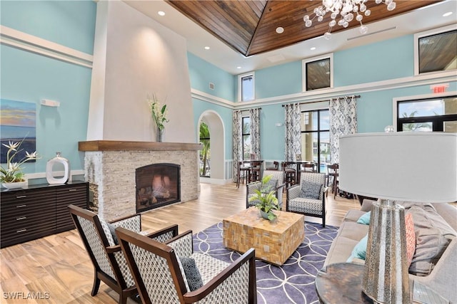 interior space featuring a high ceiling, a stone fireplace, a chandelier, and light hardwood / wood-style floors