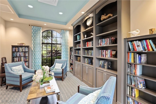 sitting room featuring light carpet and a tray ceiling