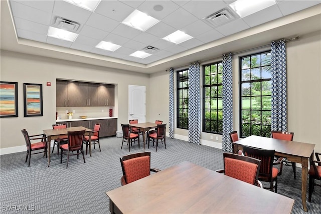 carpeted dining space featuring a paneled ceiling