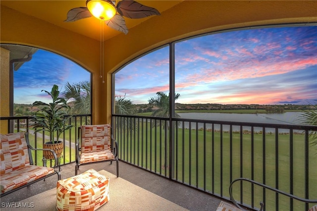 sunroom / solarium featuring ceiling fan and a water view