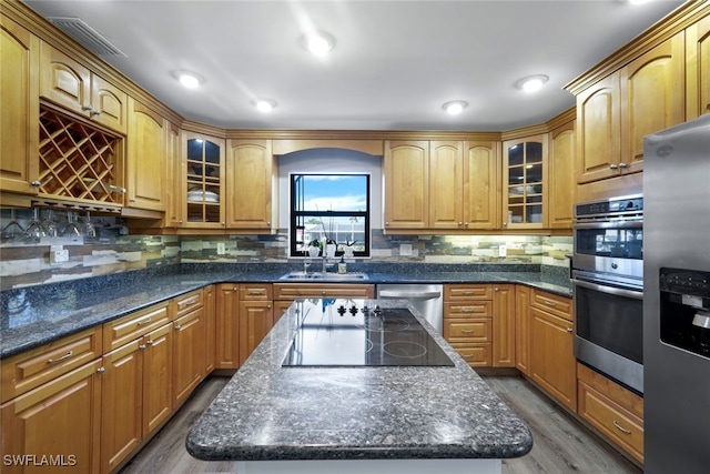 kitchen with wood-type flooring, stainless steel appliances, sink, and a kitchen island