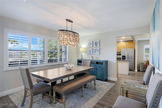 dining space featuring light wood-type flooring and an inviting chandelier