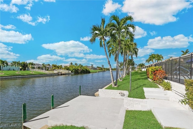 view of dock featuring glass enclosure, a yard, and a water view