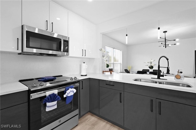 kitchen with sink, an inviting chandelier, white cabinetry, light hardwood / wood-style flooring, and appliances with stainless steel finishes