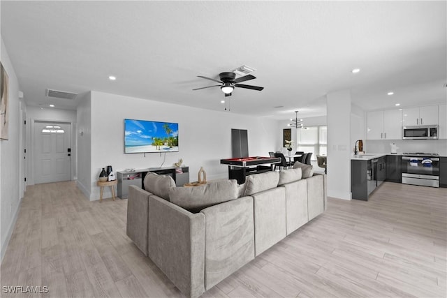 living room with ceiling fan, sink, and light hardwood / wood-style flooring