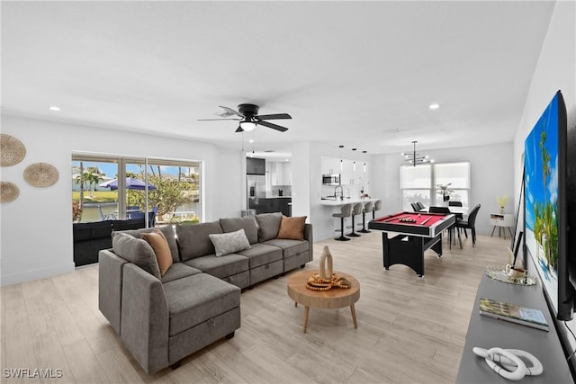 living room featuring a healthy amount of sunlight, sink, ceiling fan with notable chandelier, and light hardwood / wood-style flooring