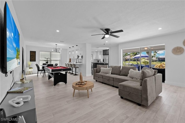 living room featuring pool table, ceiling fan with notable chandelier, and light hardwood / wood-style flooring