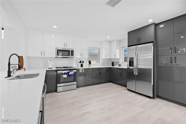 kitchen with stainless steel appliances, light hardwood / wood-style floors, white cabinetry, and sink