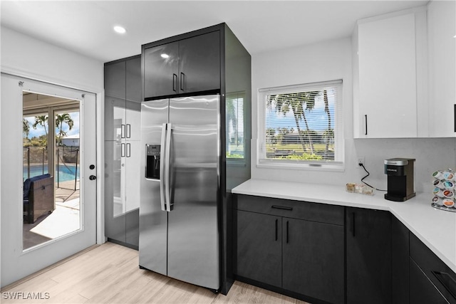 kitchen with stainless steel refrigerator with ice dispenser, plenty of natural light, and light hardwood / wood-style floors