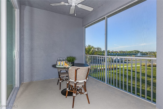 sunroom featuring ceiling fan and a water view