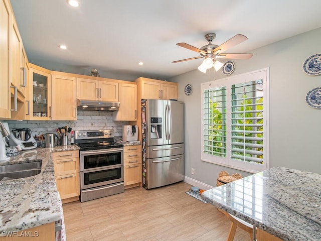 kitchen featuring light stone countertops, stainless steel appliances, tasteful backsplash, light brown cabinetry, and sink