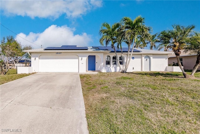 single story home featuring a front yard, solar panels, and a garage