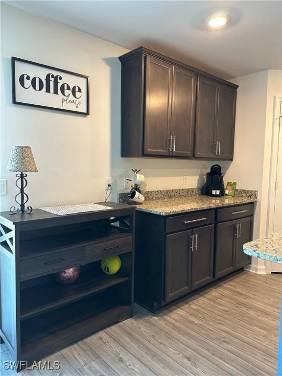 interior space with light wood-type flooring, light stone countertops, and dark brown cabinetry