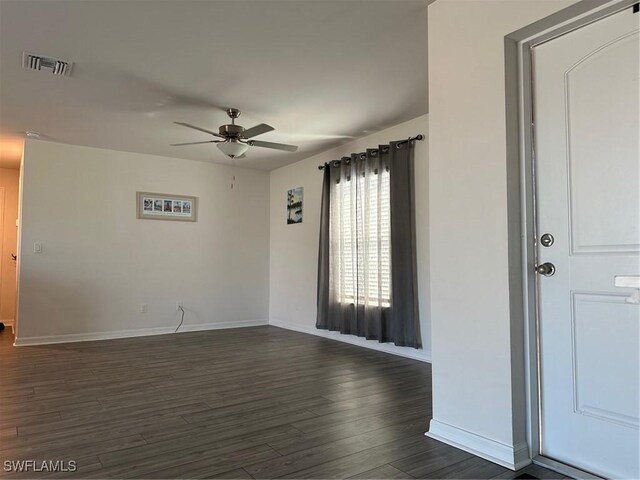 empty room with ceiling fan and dark hardwood / wood-style flooring