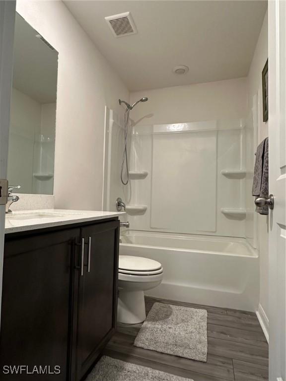 full bathroom featuring toilet, wood-type flooring, vanity, and shower / bathtub combination