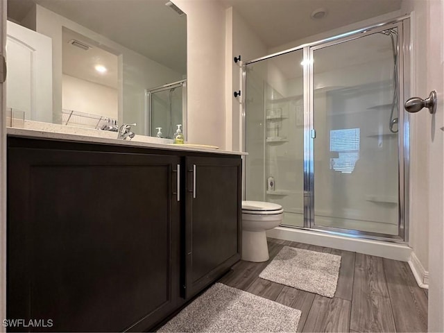 bathroom with walk in shower, hardwood / wood-style floors, vanity, and toilet