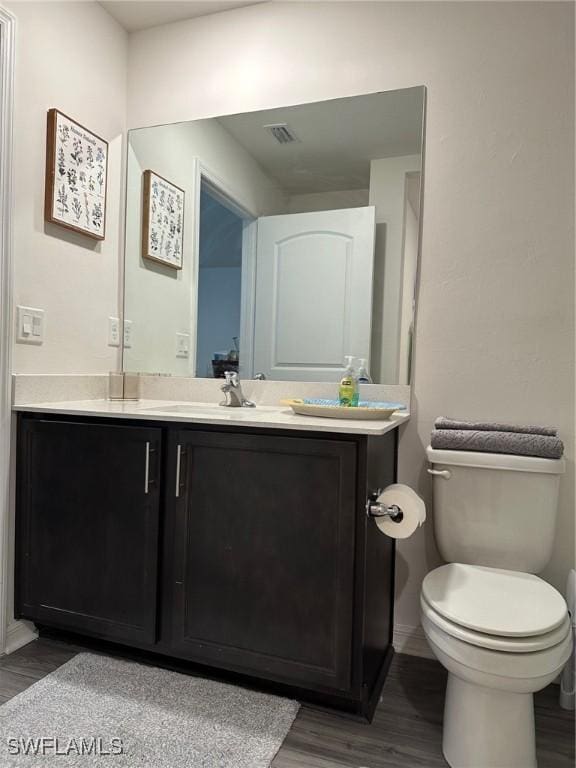 bathroom featuring toilet, hardwood / wood-style flooring, and vanity