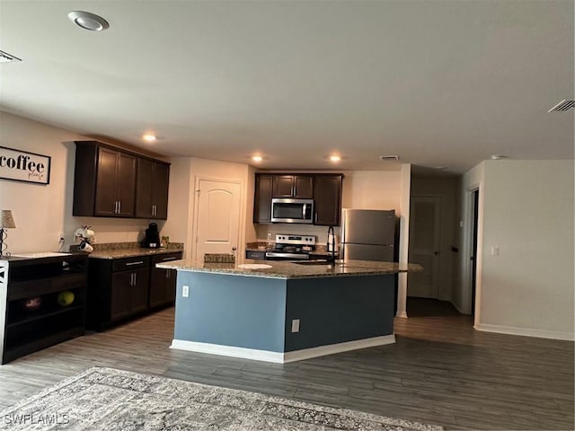 kitchen featuring a center island with sink, dark brown cabinetry, hardwood / wood-style floors, and appliances with stainless steel finishes