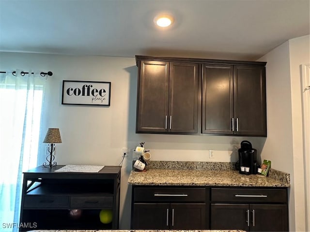 kitchen with light stone counters and dark brown cabinetry