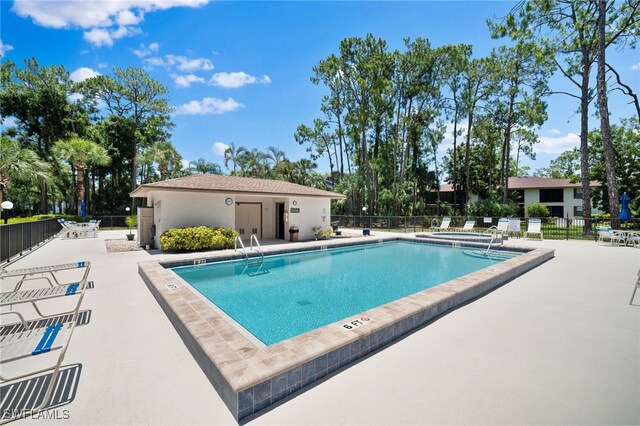 community pool with a patio, a community hot tub, and fence