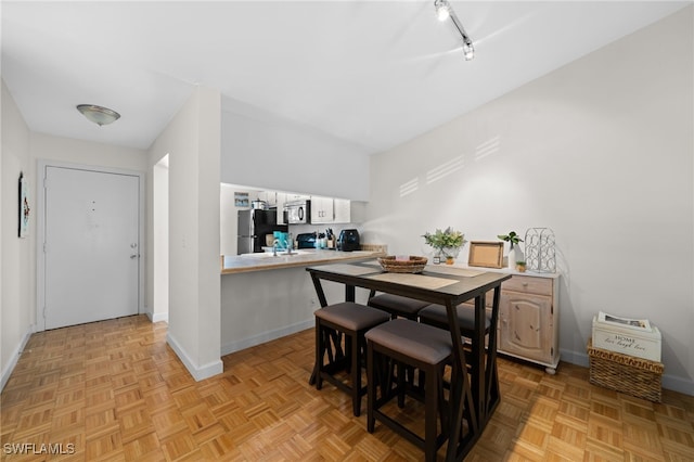 dining room with track lighting and light parquet floors