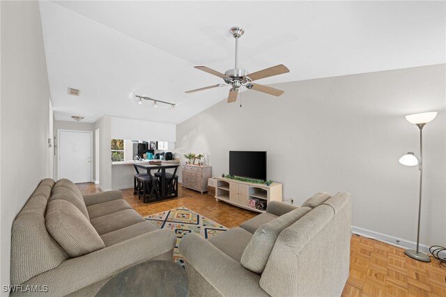 living area with ceiling fan, baseboards, visible vents, and vaulted ceiling