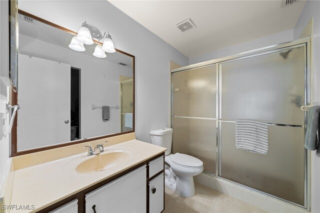 bathroom with tile patterned flooring, vanity, toilet, and a shower with shower door