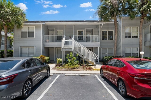 view of property featuring uncovered parking and stairway