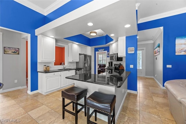 kitchen featuring white cabinets, appliances with stainless steel finishes, a kitchen breakfast bar, sink, and kitchen peninsula