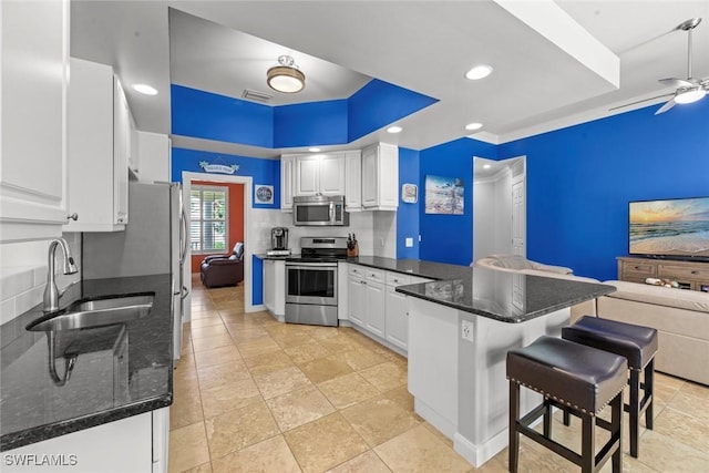 kitchen with appliances with stainless steel finishes, white cabinetry, sink, kitchen peninsula, and ceiling fan