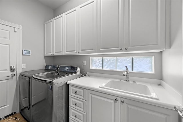 laundry area with cabinets, separate washer and dryer, and sink