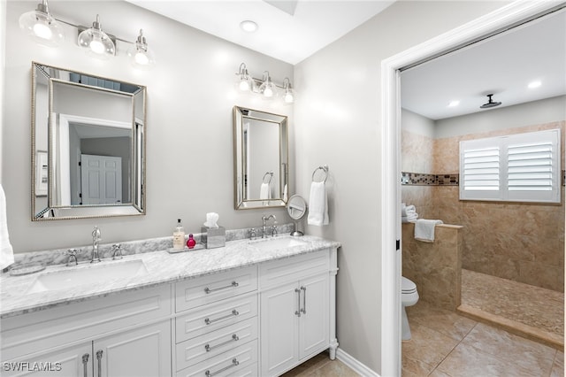 bathroom featuring tiled shower, tile patterned floors, vanity, and toilet