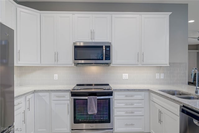 kitchen featuring decorative backsplash, appliances with stainless steel finishes, light stone counters, sink, and white cabinets