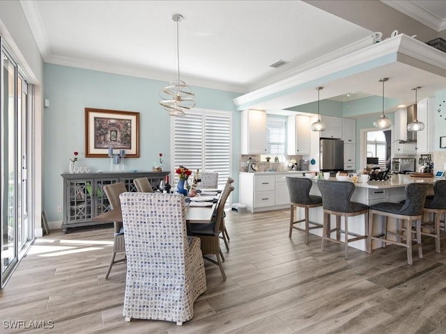 dining space featuring light wood-type flooring and crown molding