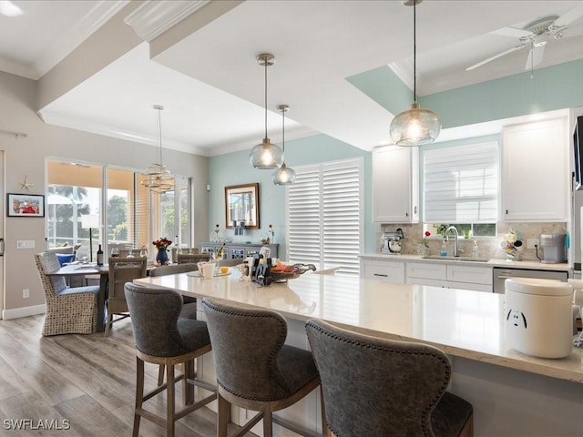 kitchen with sink, white cabinets, decorative light fixtures, ceiling fan, and light hardwood / wood-style flooring