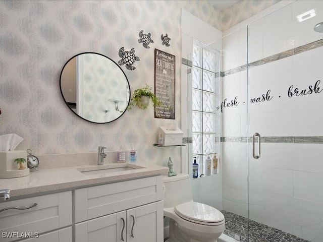 bathroom with toilet, vanity, and a shower with shower door