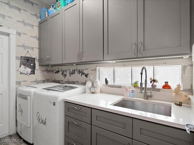 laundry area with sink, washing machine and dryer, and cabinets