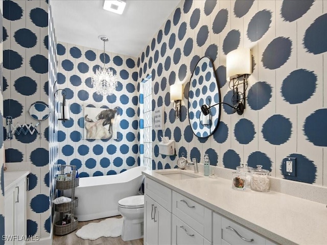 bathroom featuring toilet, an inviting chandelier, a bath, and vanity