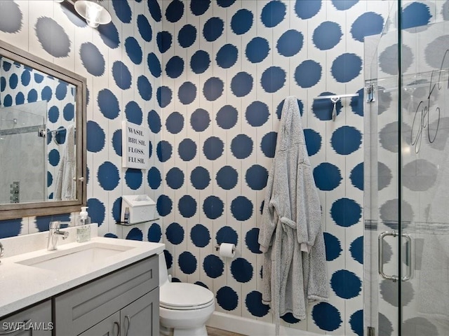 bathroom featuring toilet, a shower with door, and vanity