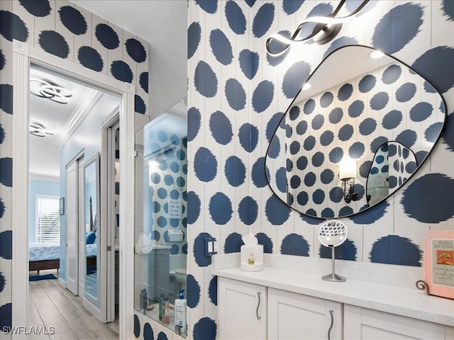 bathroom with crown molding, vanity, and wood-type flooring