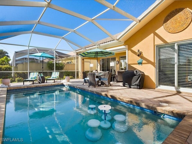 view of pool with a patio, glass enclosure, and grilling area