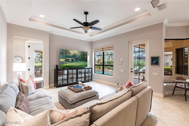 living room with ceiling fan, a tray ceiling, and ornamental molding