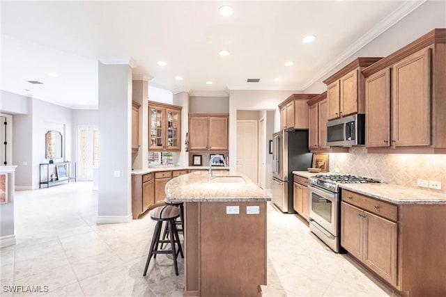 kitchen featuring light stone countertops, stainless steel appliances, sink, a center island with sink, and a breakfast bar area